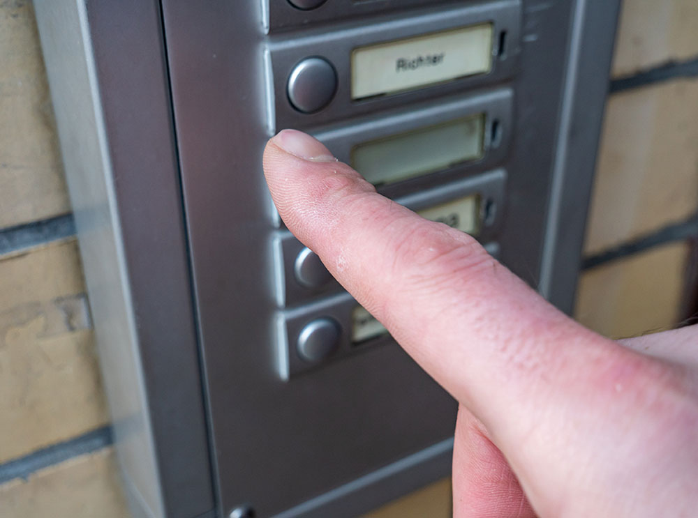 Finger drückt eine Klingel