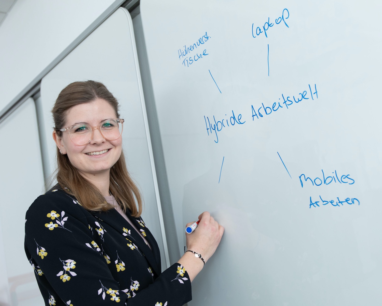 Mitarbeiterin steht vor einem Whiteboard mit Begriffen