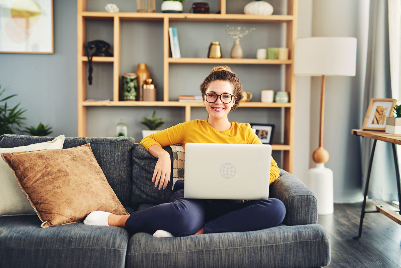 Junge Frau sitzt mit Laptop auf dem Sofa
