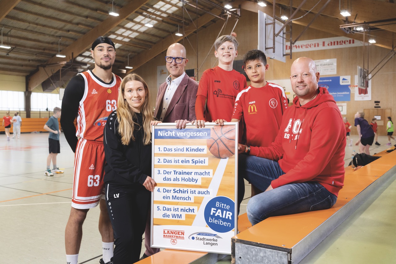 Eine Gruppe von Personen, darunter mehrere Vereinsmitglieder, stehen um ein Plakat zum Thema "Fair bleiben im Sport"