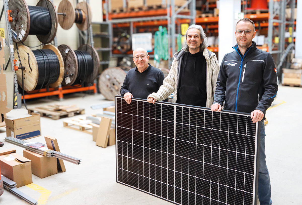 Drei Männer in einer Werkstatt stehen vor einem Photovoltaikanlagen-Modul