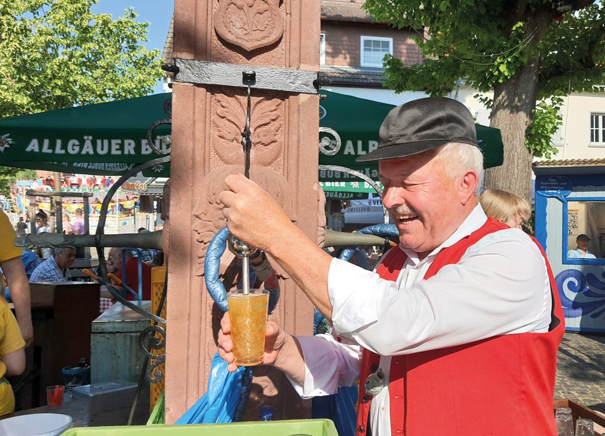Mann zapft Bier an einem Brunnen
