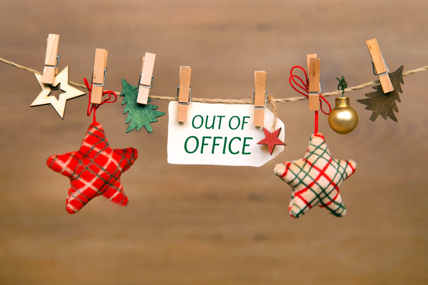 Ein Faden von links nach rechts gespannt an dem mit kleinen Wäscheklammern Weihnachtsdeko hängt und ein Schild mit der Aufschrift "out of office".